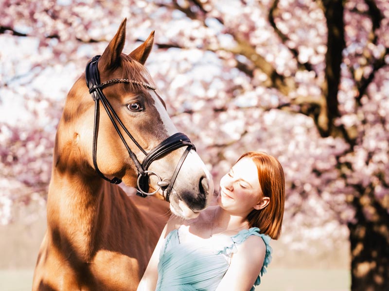 Portrait rothaariges Mädchen mit Pony vor Kirschblüten