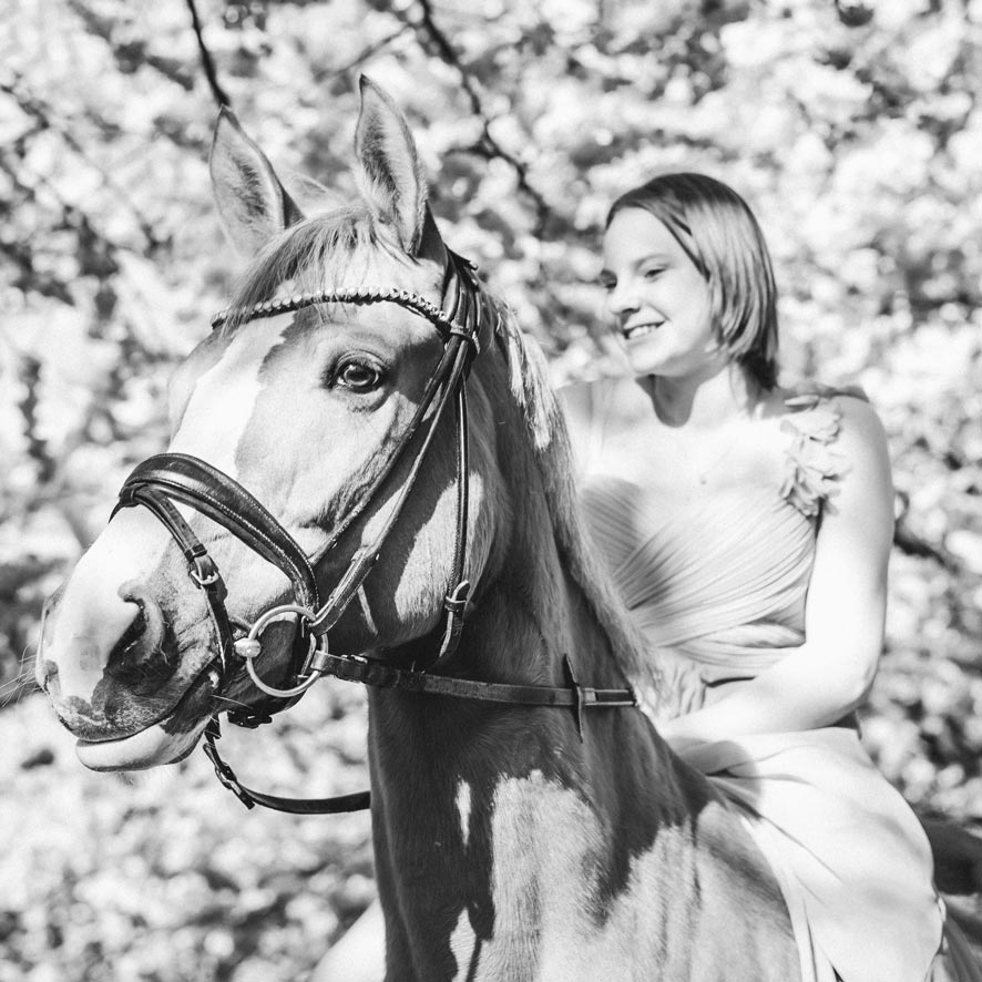 Schwarzweiss Portrait eines jungen Mädchens auf ihrem Pony vor Kirschbaum